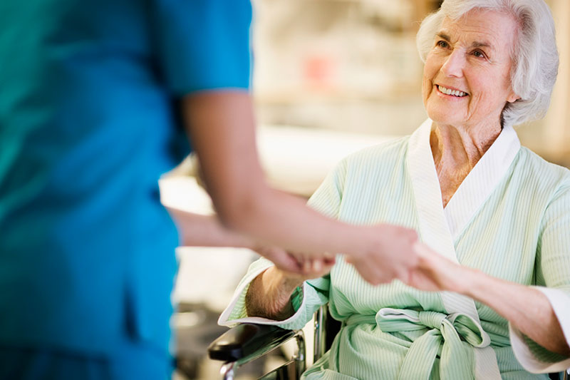 Care worker holds the hands of an older lady