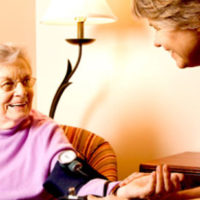 Older lady smiles whilst having her blood pressure taken