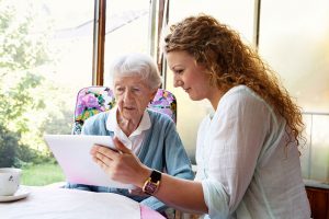 A nurse shows an older patient information on a tablet