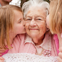 An older woman is kissed on the cheeks by two children