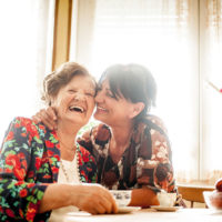 two women laughing over a cup of tea