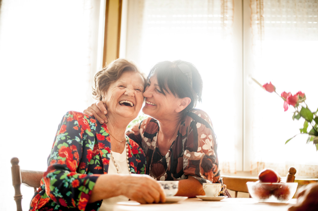 two women laughing over a cup of tea