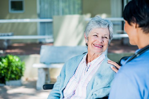 Smiling older woman speaks with doctor outside